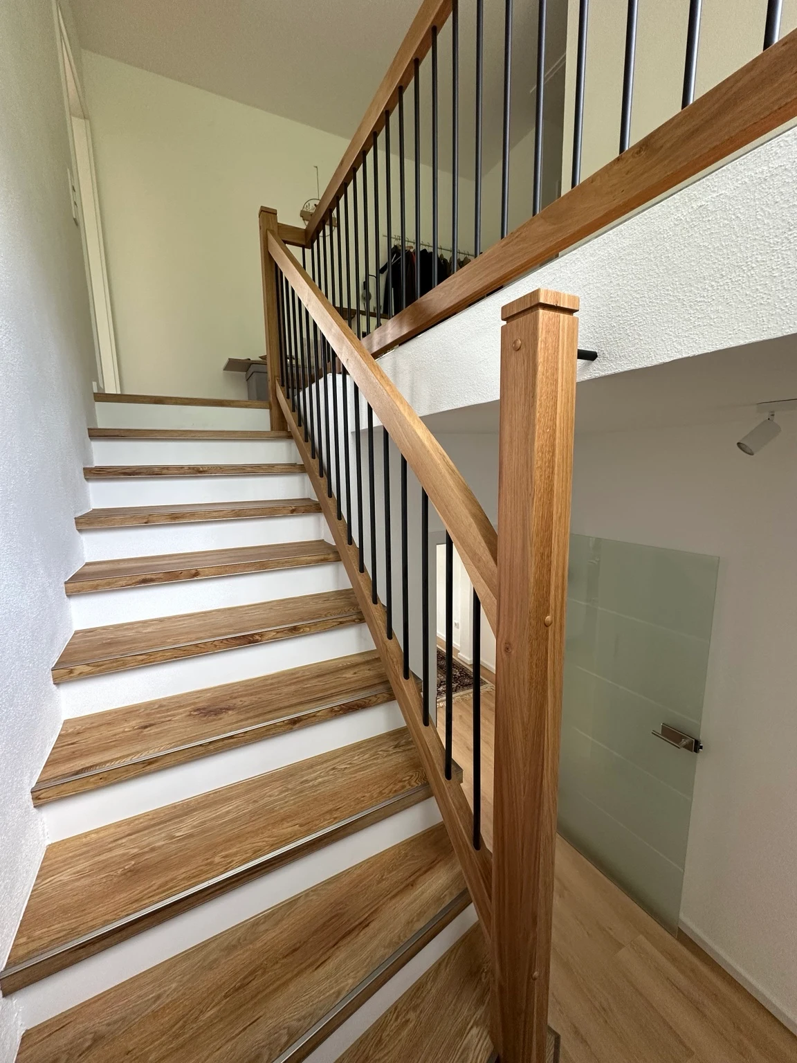 Holztreppe mit Eichenstufen und schwarzen Geländerstäben